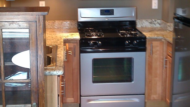 Una cocina con armarios de madera, una estufa de acero inoxidable, un microondas y un refrigerador.