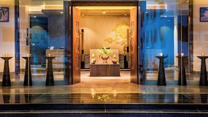A hotel lobby with a reception desk, a coffee table with decorative items, and a large window with a view.