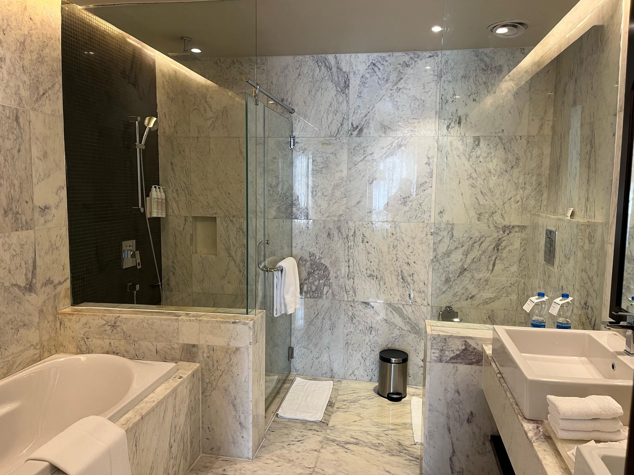 Un baño moderno con ducha envuelta en cristal, una bañera y dos lavamanos.