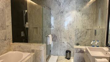 Un baño moderno con ducha envuelta en cristal, una bañera y dos lavamanos.