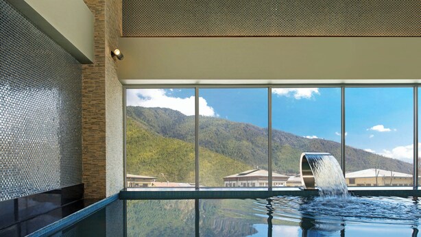A serene indoor pool with a clear view of mountains through large windows.