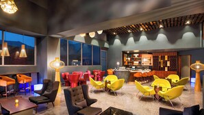 A modern lounge area with seating arrangements, a bar, and a view of the outdoors.