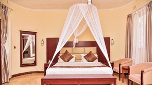A bedroom with a four-poster bed, a bedside table, a chair, and a mirror on the wall. - Chamba Valley Exotic Hotel (Lusaka)