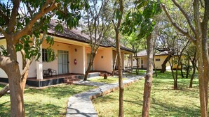 A building with a tiled roof, a covered outdoor seating area, and a paved walkway. - Chamba Valley Exotic Hotel (Lusaka)