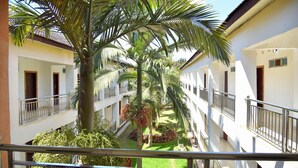 A multi-story building with balconies, a central courtyard with palm trees, and a well-maintained lawn. - Chamba Valley Exotic Hotel (Lusaka)