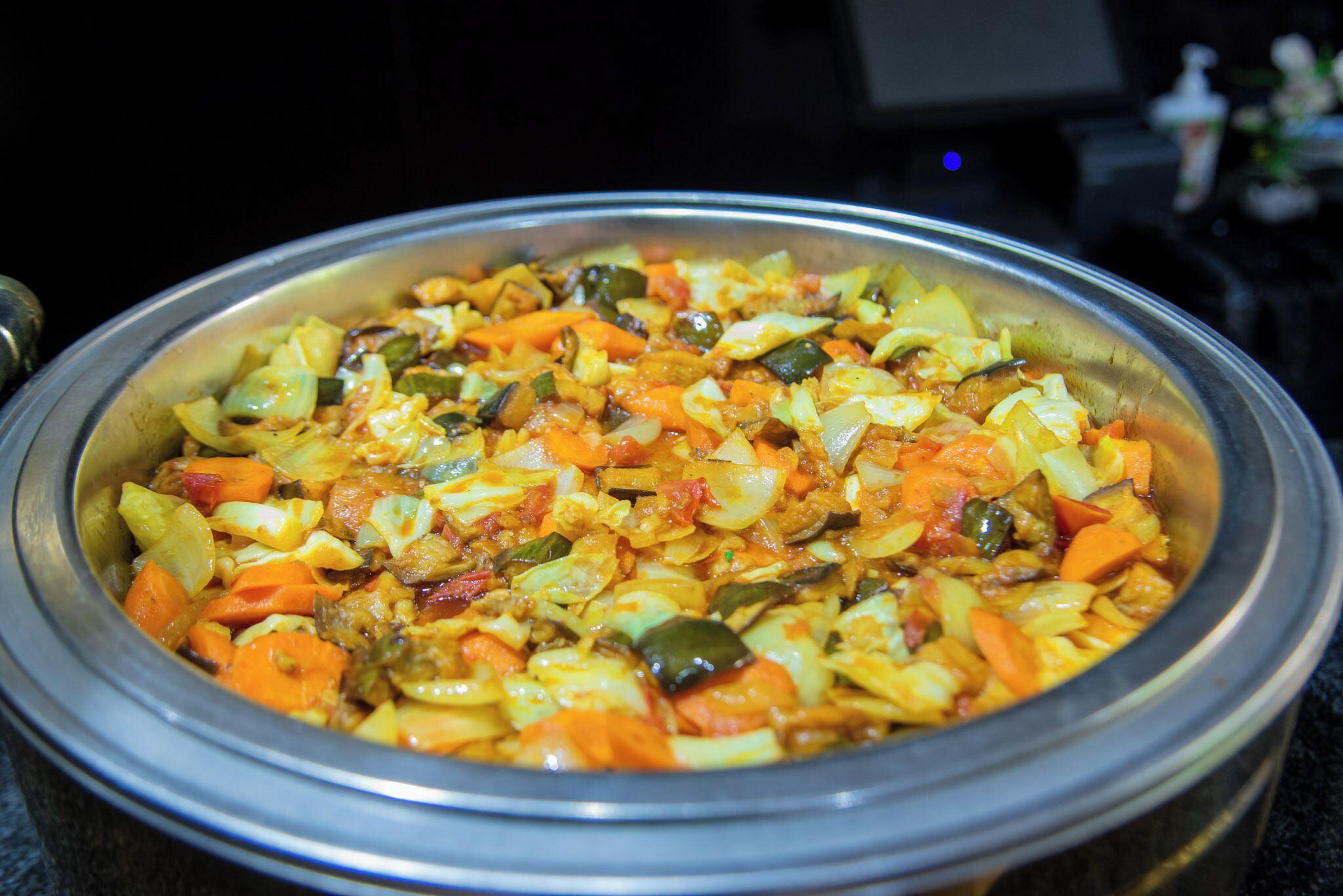 A large metal bowl filled with a colorful vegetable dish.