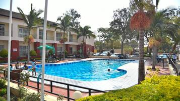 Relax by the hotel's large rectangular pool surrounded by a deck and palm trees.