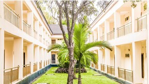 A building with multiple floors, balconies, and a central courtyard with palm trees and a lawn. - Chamba Valley Exotic Hotel (Lusaka)