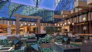 Un hall d’entrée spacieux, doté de meubles modernes, d’un atrium en verre et de plantes d’intérieur.