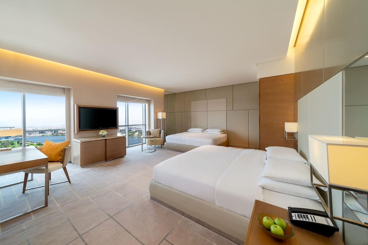 Ein Hotelzimmer mit einem großen Bett, einem Schreibtisch, einem Fernseher und Blick auf die Stadt.