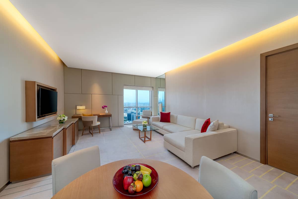 Ein modernes Hotelzimmer mit Essbereich, einer Sitzecke, einem Fernseher und Blick auf die Stadt.