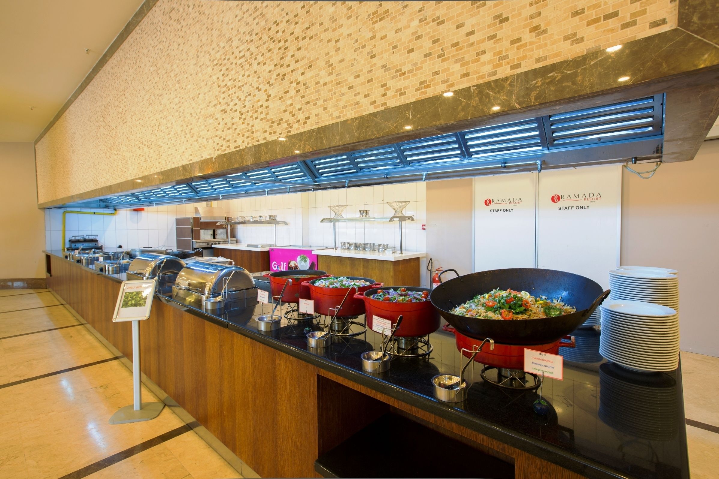 A buffet area with multiple food stations, including a wok station and a salad station, with signs indicating staff-only areas.