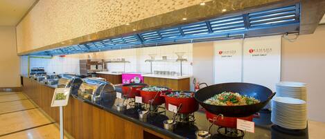 A buffet area with multiple food stations, including a wok station and a salad station, with signs indicating staff-only areas.