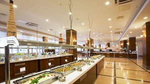 Uma área de buffet com diversas estações de comida, incluindo saladas e pratos quentes, em ambiente interno bem iluminado com detalhes em madeira e decoração moderna.