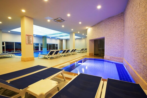 An indoor swimming pool with lounge chairs and a tiled floor. - Ramada Resort by Wyndham Side (Manavgat)