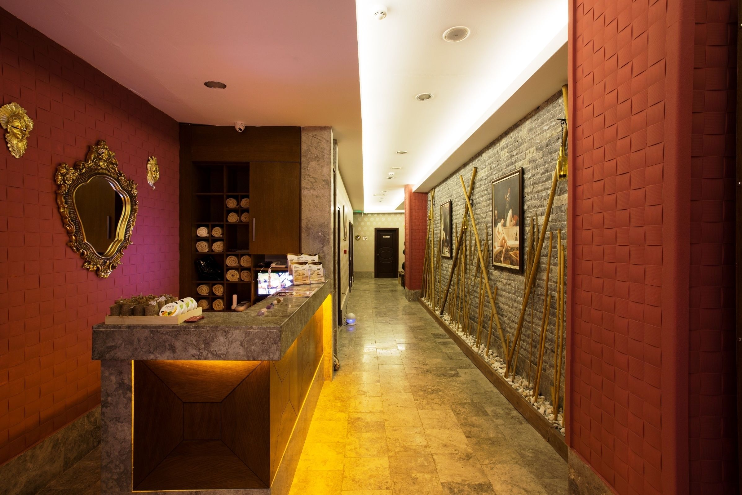 A hotel reception area with a marble counter, a mirror, and a wall-mounted display of circular items.