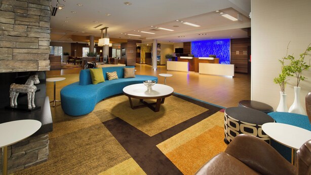 Een moderne lobby met een blauwe bank, een open haard en een receptiebalie.