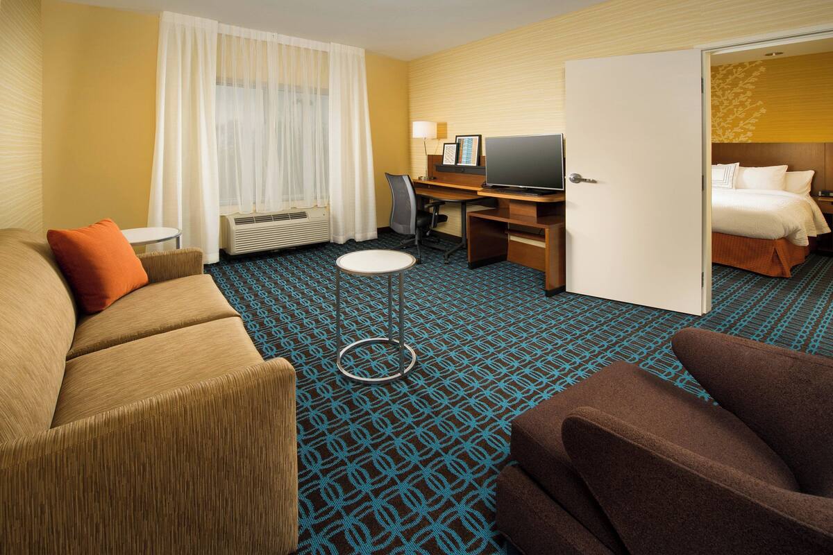 Habitación de hotel con cama, escritorio, televisor, silla y sofá.