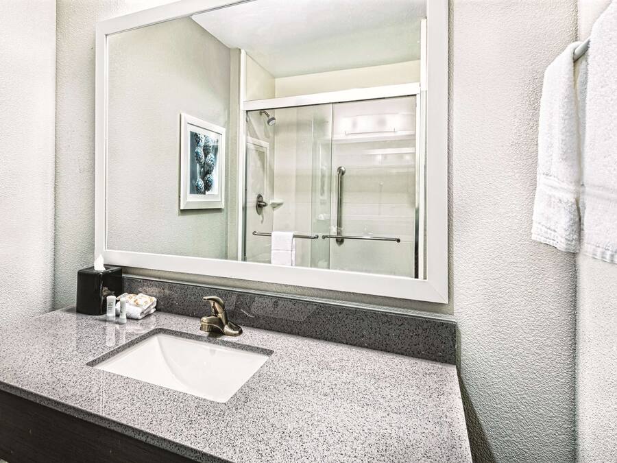 A bathroom with a large mirror, a sink, and a shower.