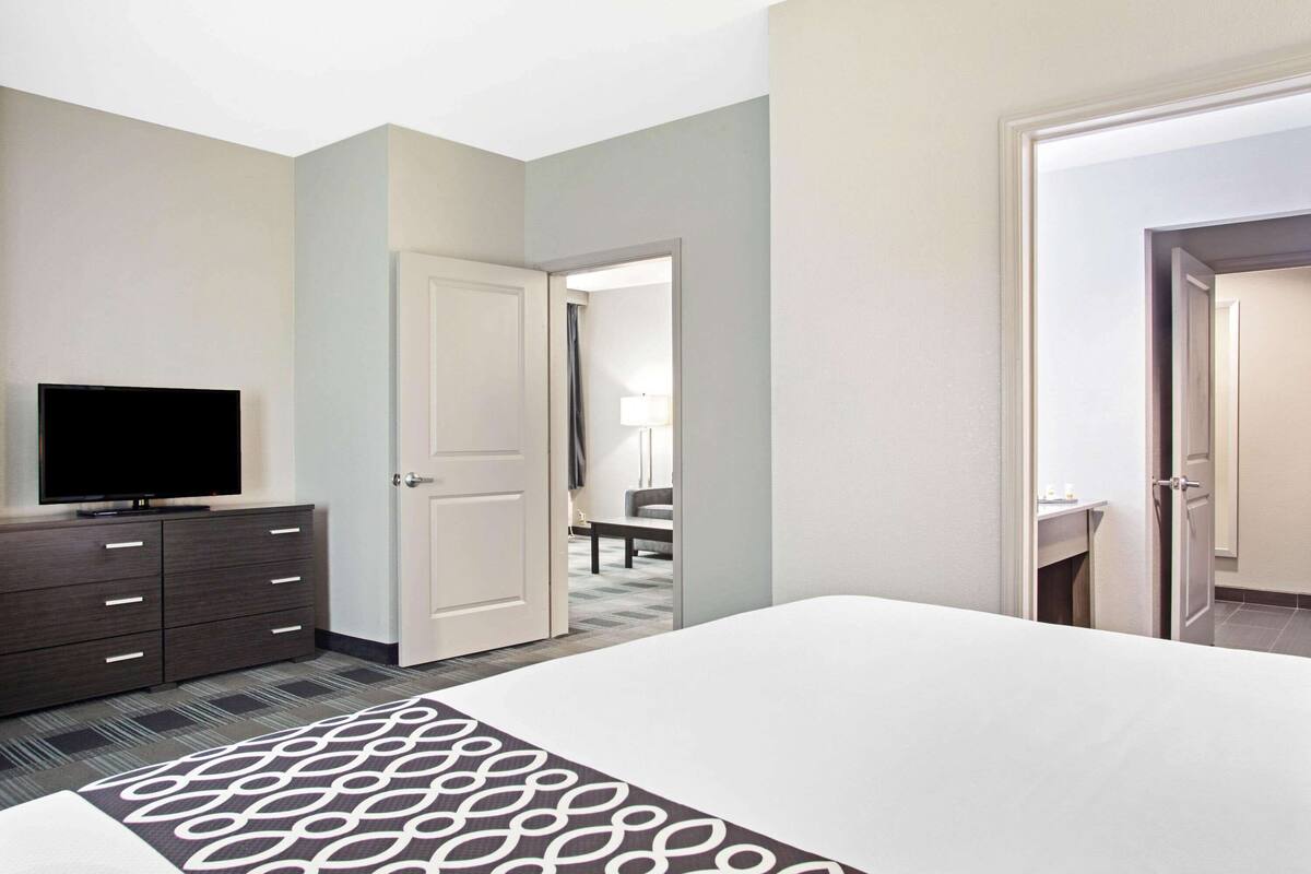 Une chambre d’hôtel avec un lit, un téléviseur posé sur une commode et une porte donnant sur une salle de bain.