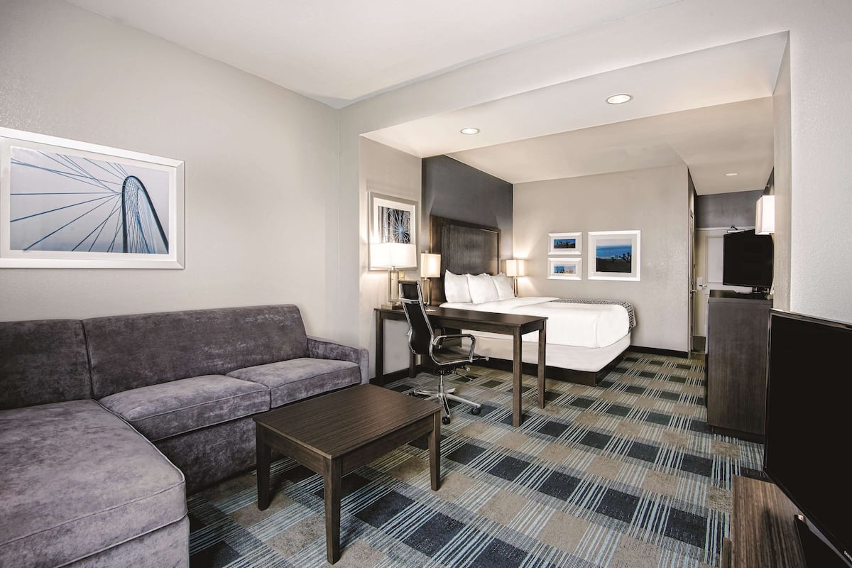 Une chambre d’hôtel avec un lit, un canapé, un bureau et une télévision.