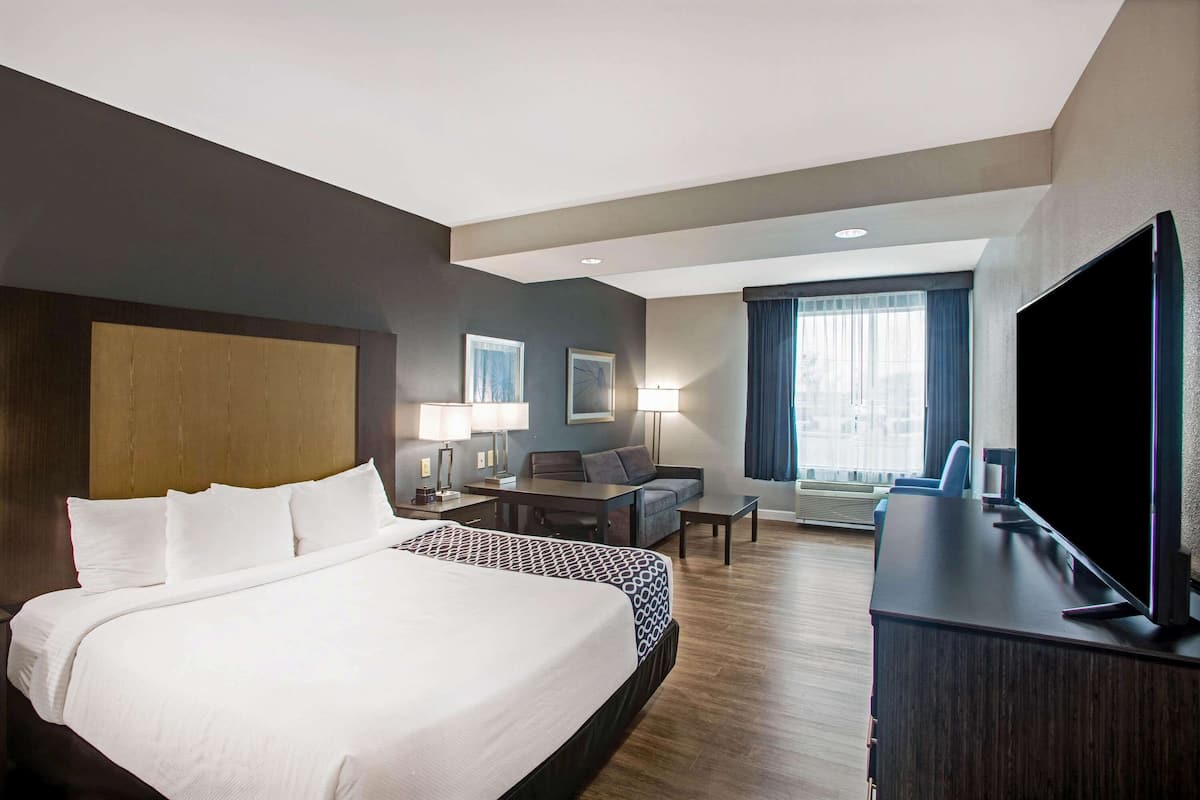 Une chambre d’hôtel avec un grand lit, un bureau, une télévision et un coin salon.
