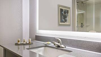 A modern bathroom with a granite countertop, a silver faucet, and a framed artwork above the mirror.