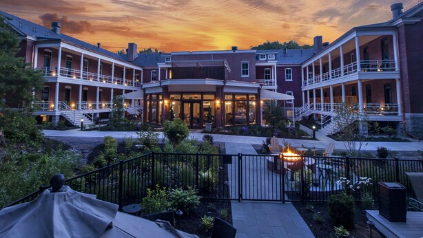 A large, multi-story building with a central courtyard, featuring a fire pit and outdoor seating area. - Inn at Diamond Cove (Portland)