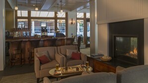 A cozy lounge area with a fireplace, comfortable seating, and a bar with wooden stools. - Inn at Diamond Cove (Portland)