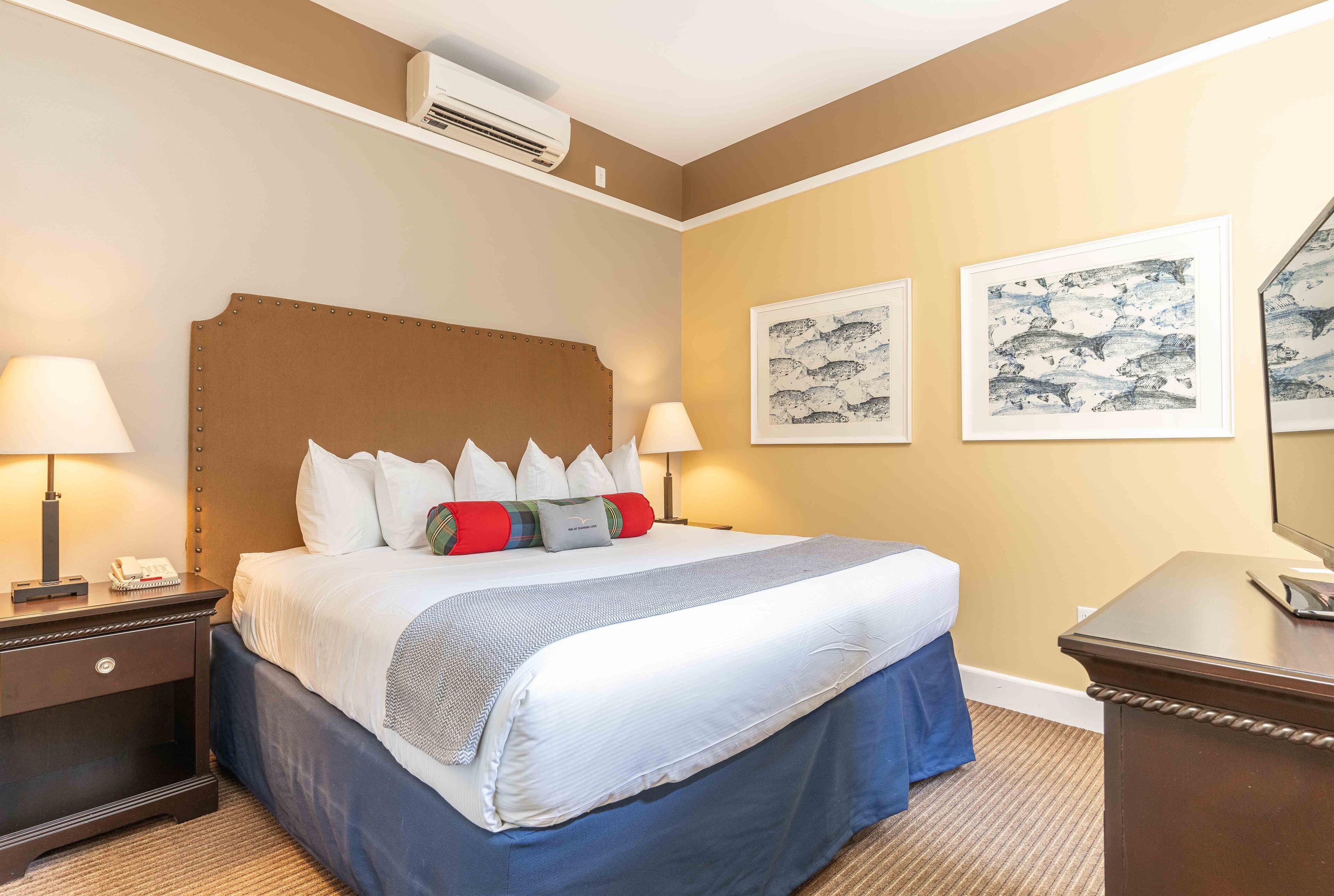 Ein Hotelzimmer mit einem großen Bett, zwei Nachttischlampen, einem Nachttisch und einem Schreibtisch mit Stuhl.