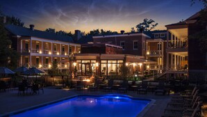 A pool area with lounge chairs and a building with multiple levels and outdoor seating. - Inn at Diamond Cove (Portland)