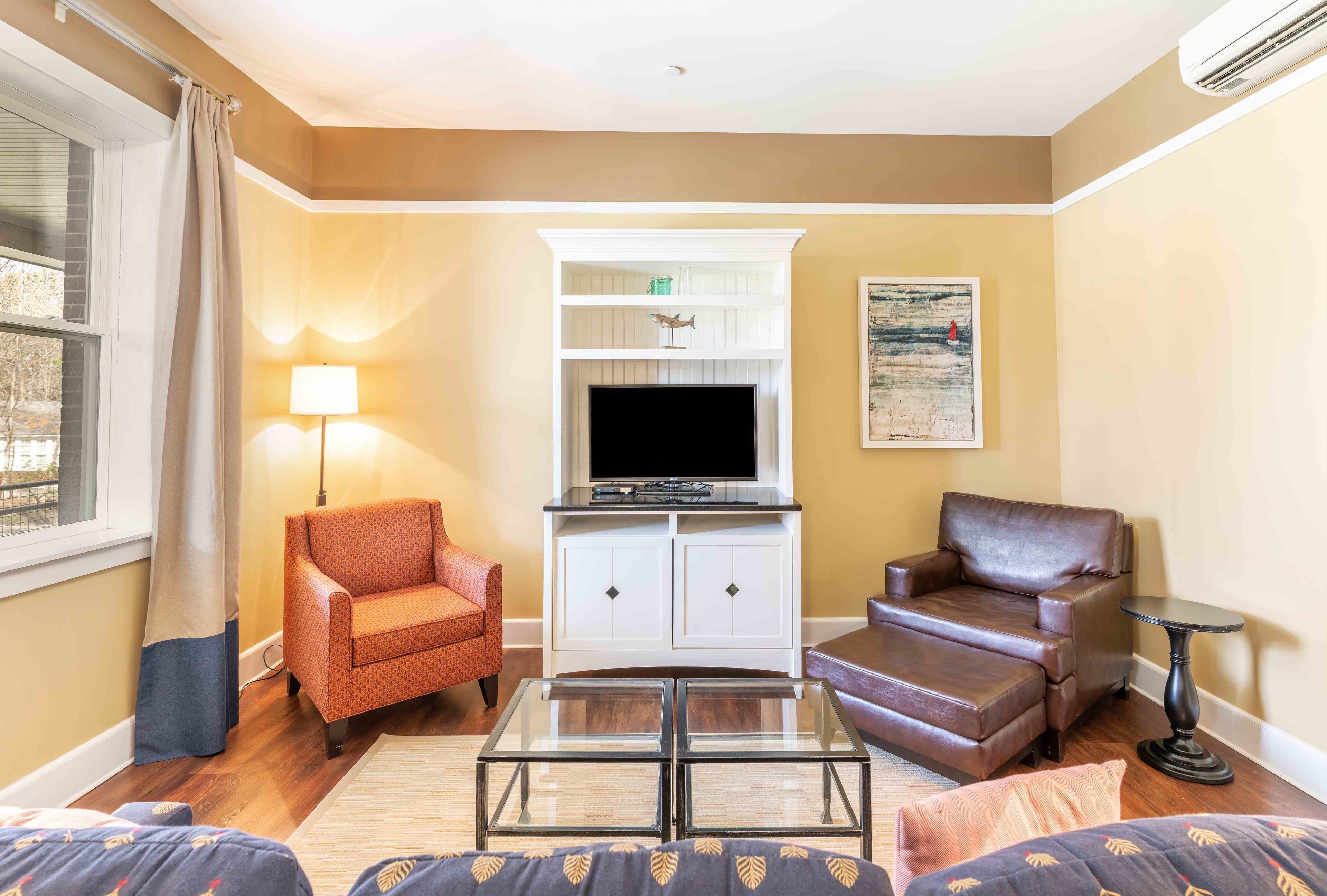 A living room with a television, two chairs, a coffee table, and a lamp.