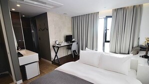 A hotel room with a large bed, a desk with a computer, a chair, a small sink, and a wardrobe. - Circle Hotel Seoul (Seoul)