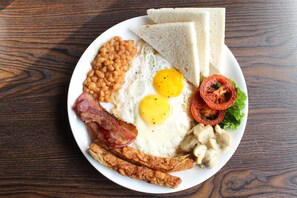A plate of breakfast food including eggs, bacon, beans, toast, and tomatoes. - The Nana Hotels (Kathmandu)