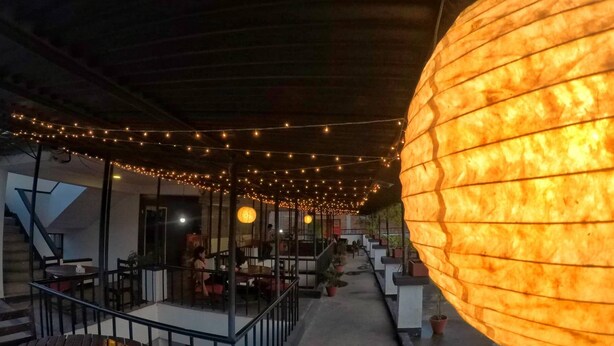 An outdoor seating area with string lights and a large illuminated lantern. - The Nana Hotels (Kathmandu)