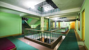 A multi-level interior with green walls, a central staircase, and a mezzanine with a railing. - The Nana Hotels (Kathmandu)