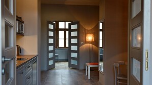 A hallway with a kitchen area, a dining table, and a chair.