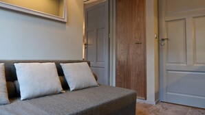 A modern living room with a grey sofa, two white cushions, and wooden paneling on the wall.