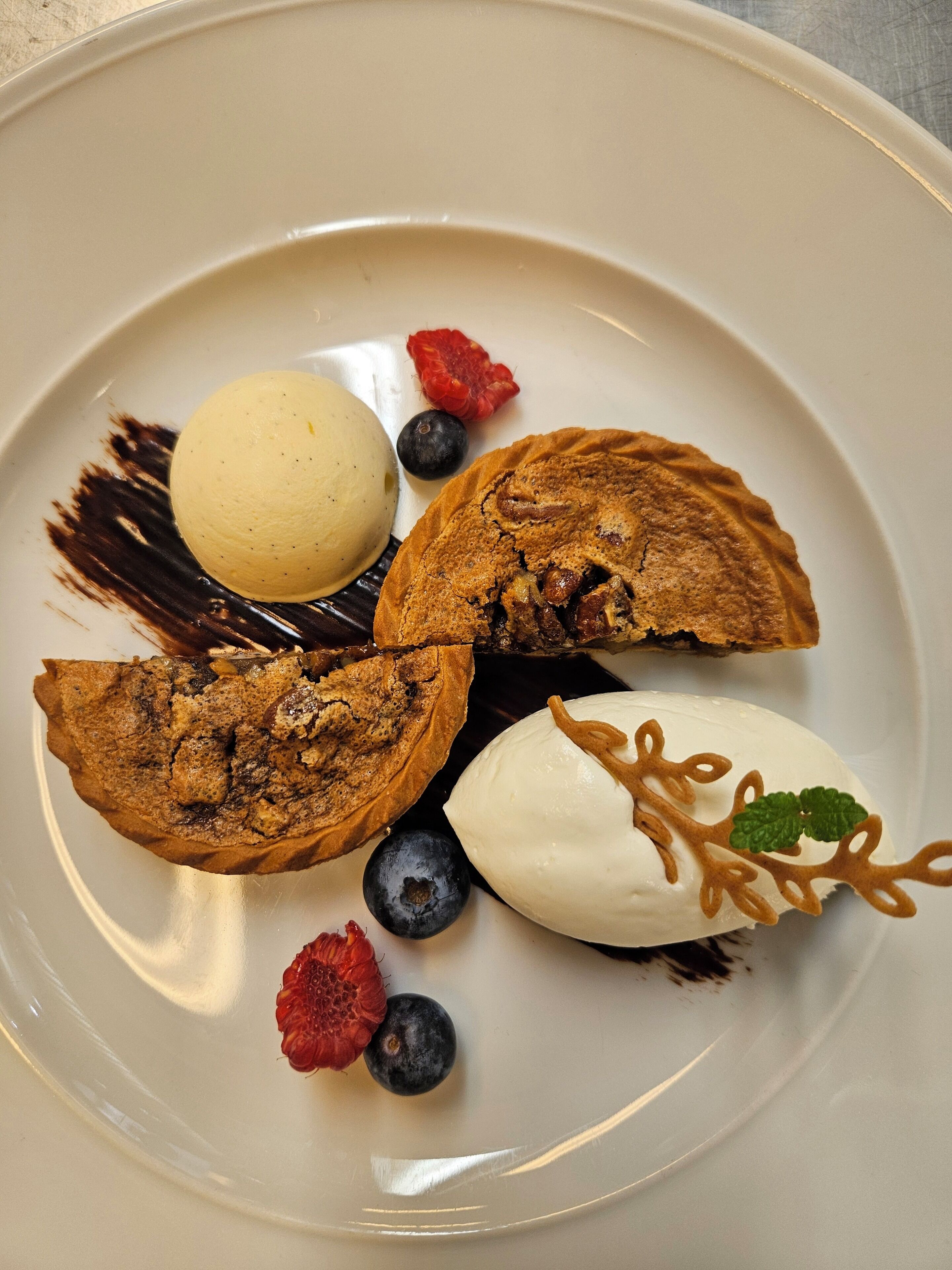En desserttallrik med en skopa vaniljglass, en bit chokladkaka och färska bär.