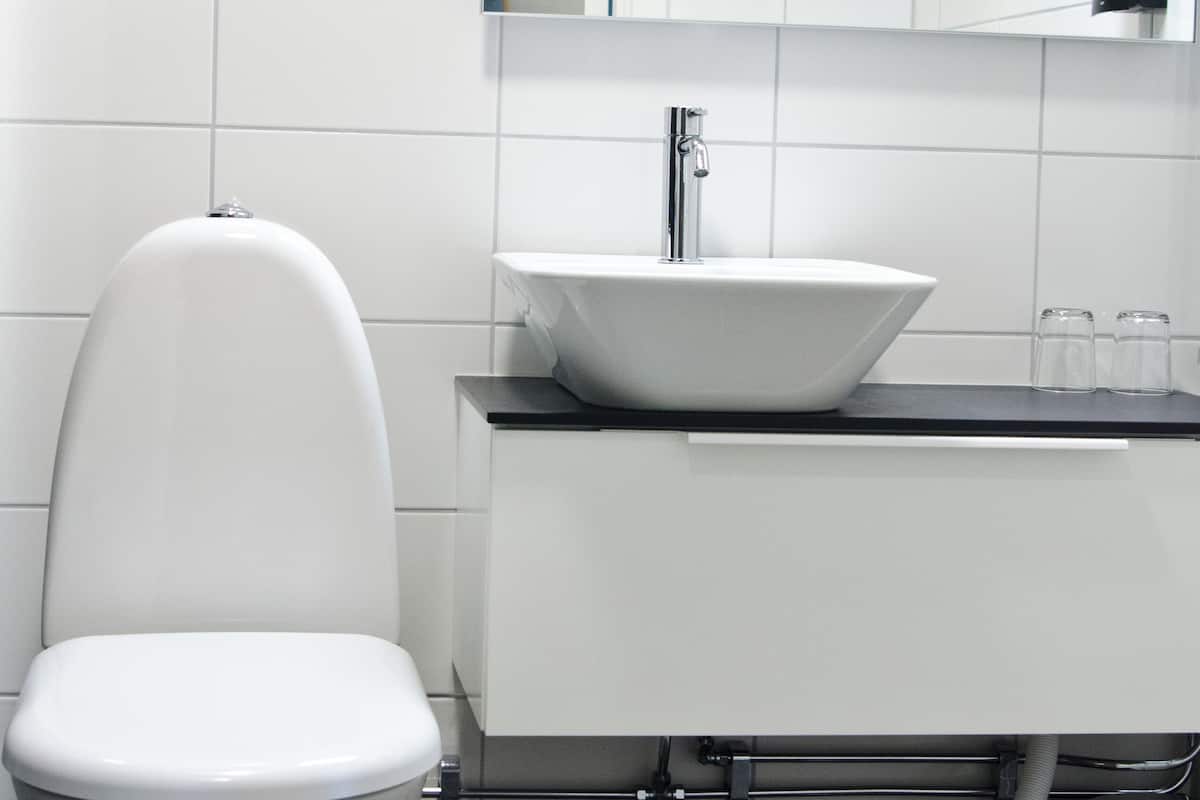 Ein modernes Badezimmer mit Toilette, einem Aufsatzwaschbecken und einem Spiegel über dem Waschbecken.