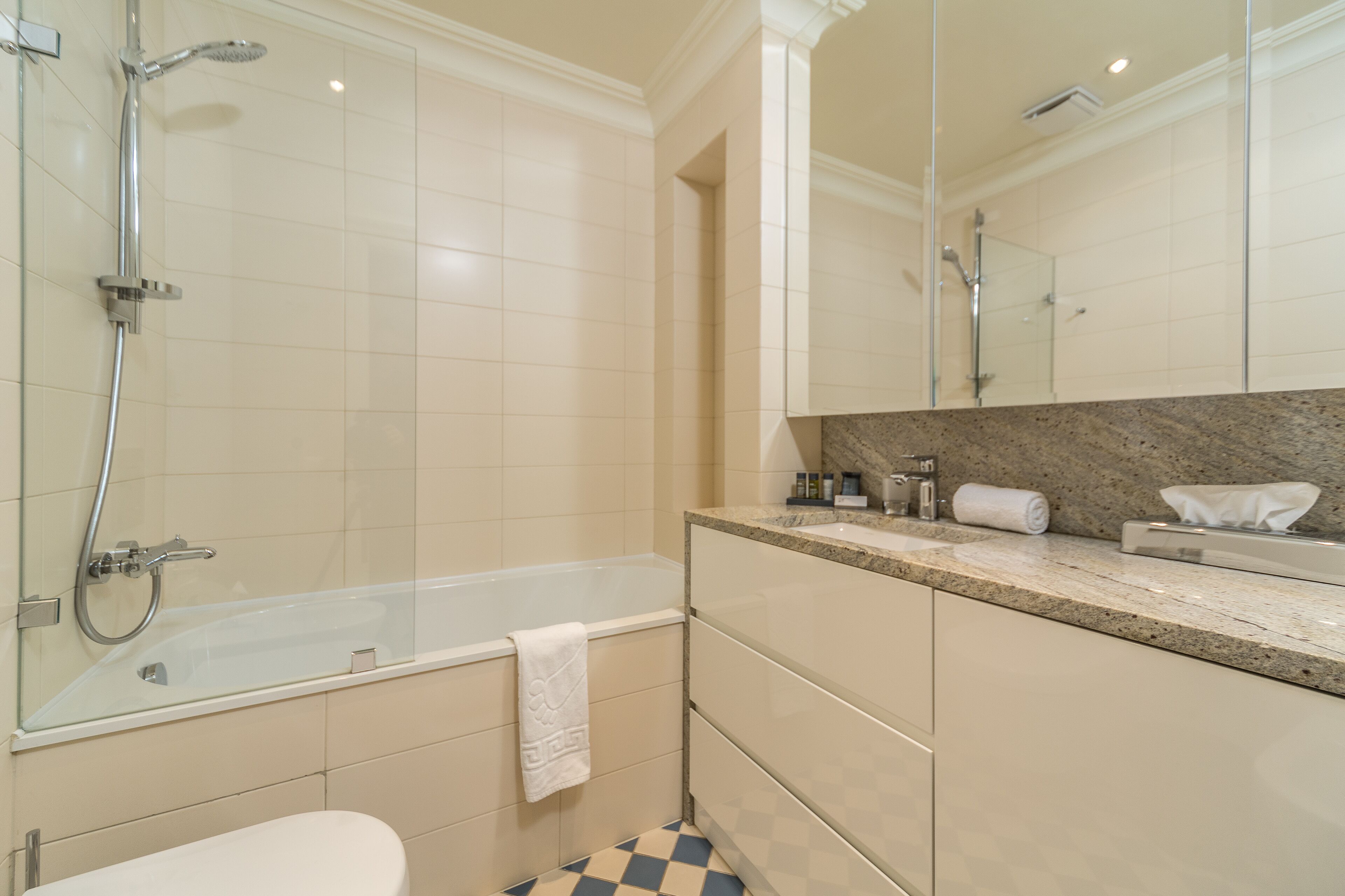 Ein modernes Badezimmer mit einer in Glas eingefassten Badewanne, einer Dusche und einem großen Spiegel über dem Waschbecken.