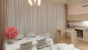Een eetgedeelte met een tafel gedekt voor vier personen, een kroonluchter en een keuken op de achtergrond.
