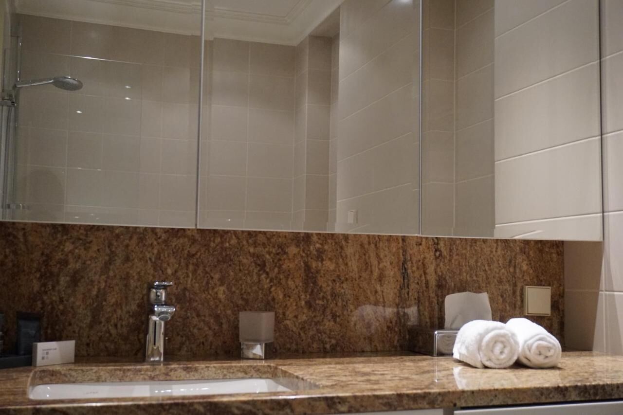 Un baño con encimera de mármol, un lavabo, un espejo y un perchero con toallas.