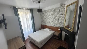 Un dormitorio con cama, mesita de noche, silla y espejo.