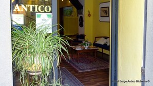 Una habitación con una planta grande en maceta, una mesa de madera, un sofá y una cama.