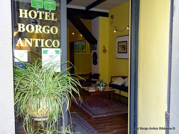 A room with a large potted plant, a wooden table, a sofa, and a bed. - Hotel Borgo Antico Bibbiena (Bibbiena)