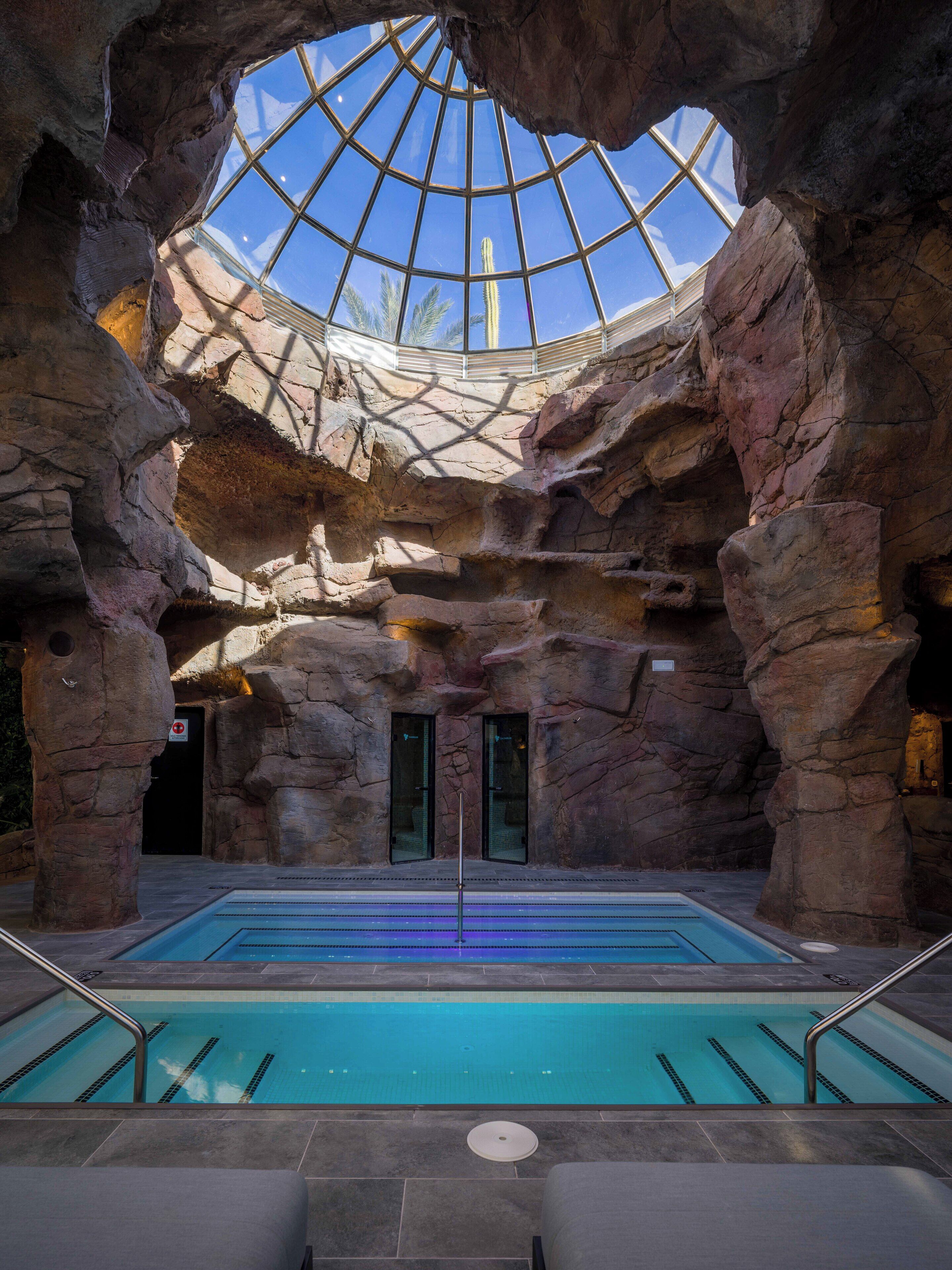 An indoor pool with a glass ceiling, surrounded by rock formations.