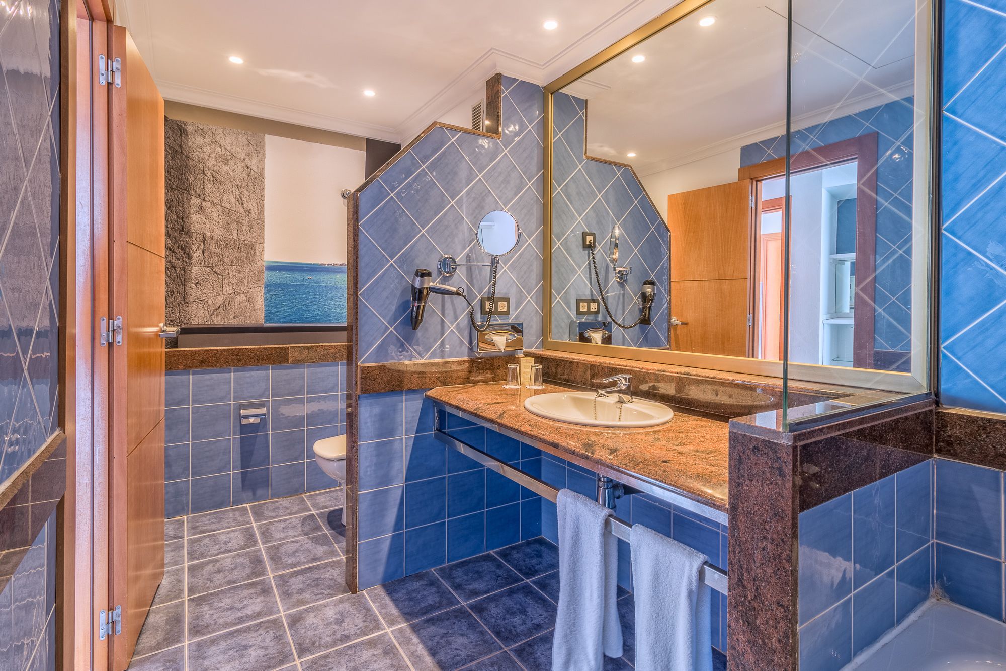 A modern bathroom with a large mirror, a sink, and a shower.