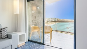 A modern room with a glass door leading to a balcony with a view of the sea.