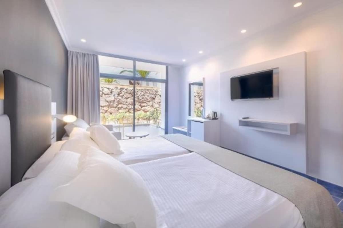 Une chambre d’hôtel avec un grand lit, un téléviseur fixé au mur et une vue sur l’extérieur.